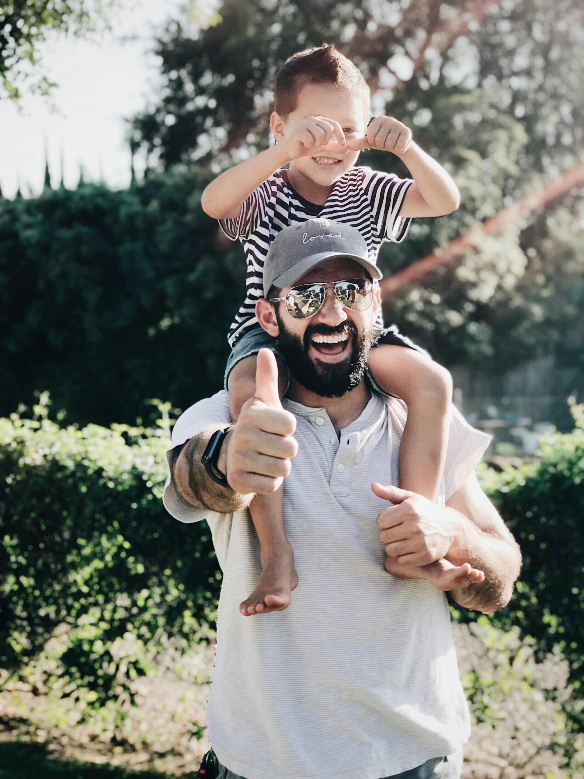 Father holding his son on his shoulders and giving a thumbs up